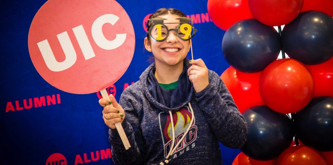 Student posting for photo with UIC logo and funny glasses