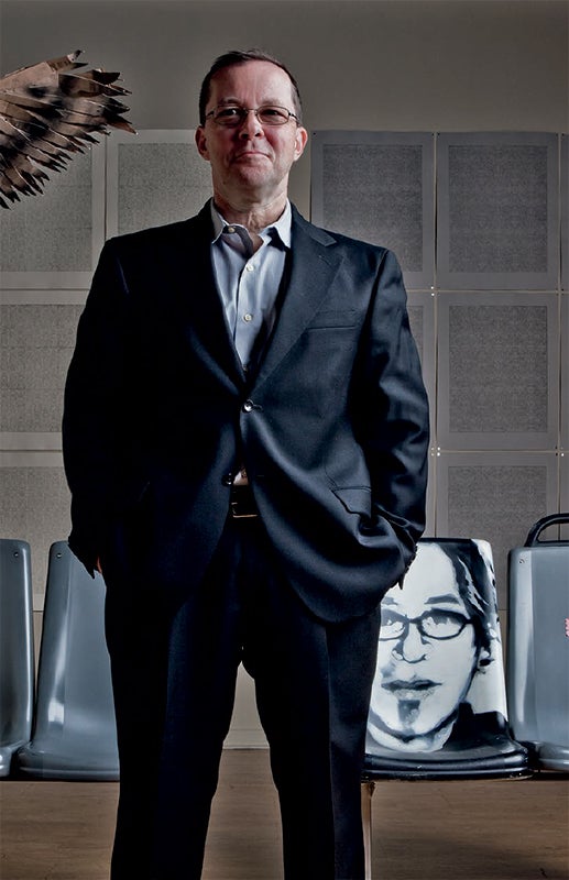 Photo of UIC alumnus and artist Jim Duignan standing in front of a portrait of UIC alumnus and artist Mike Piazza