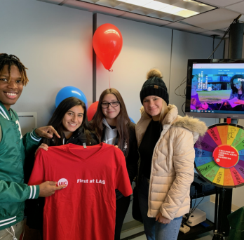 Four students posing for a photo holding a red t-shirt with the First at LAS UIC logo 