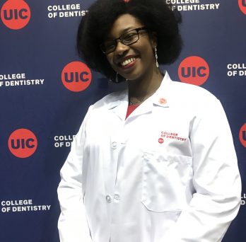 student in dental lab coat smiling 