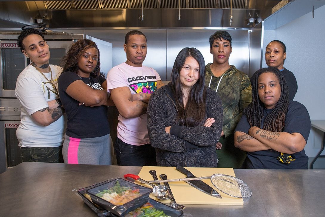 seven people standing behind a chef's table posing for the camera