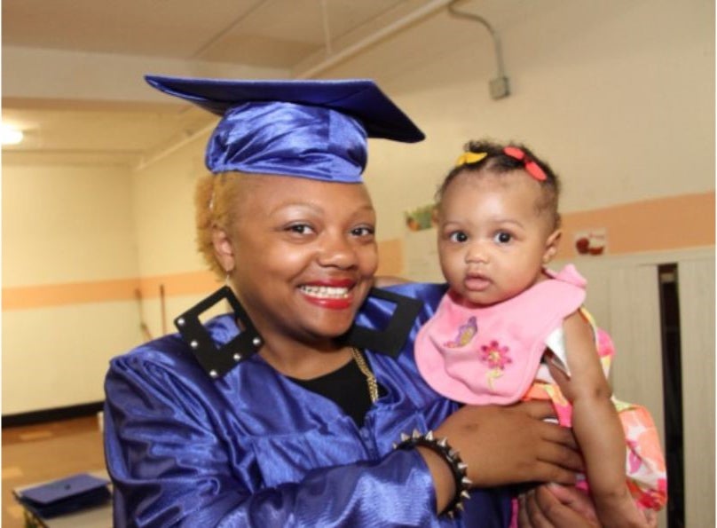 Woman in graduation gown holding a baby