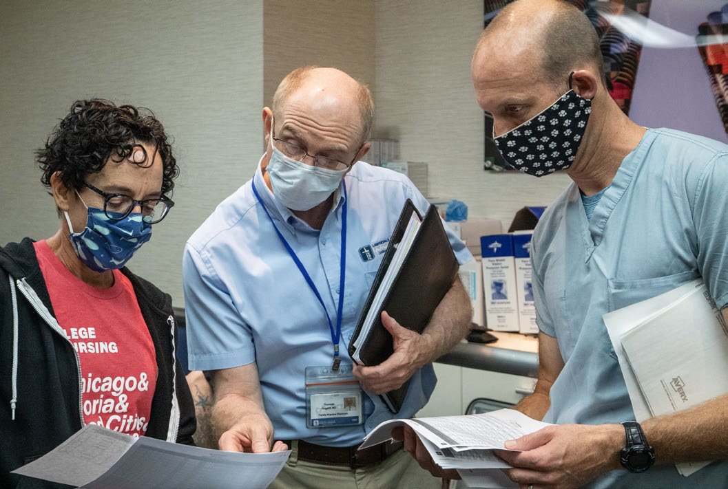 Rebecca Singer, clinical assistant professor of nursing at UIC; Dr. Thomas Huggett, physician at Lawndale Christian Health Center; and Dr. Stockton Mayer, UI Health infectious disease specialist, review the testing plan for the Unsheltered Chicago Coalition at Hotel One Sixty-Six.