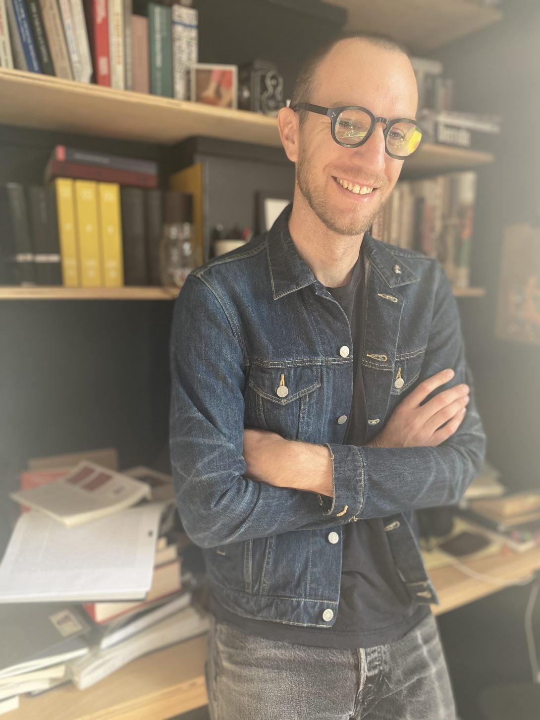 A person standing in front of bookshelf smiling