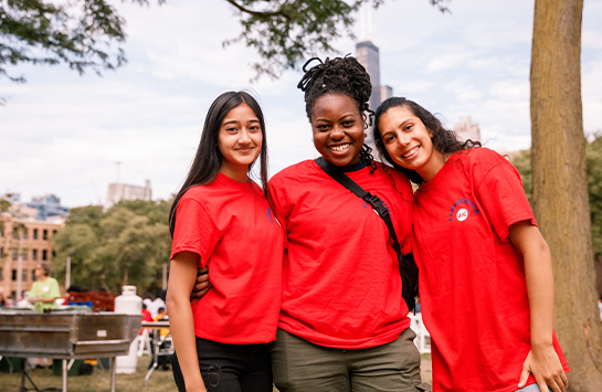Three students in red t-shirts smiling