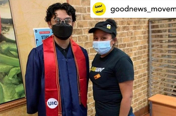 A UIC student in graduation cap and gown taking a photo with a Subway employee at the Subway sandwich shop.