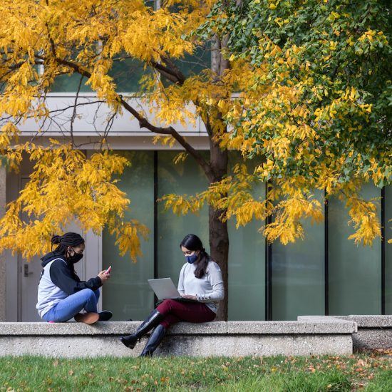 Two women outside studying.