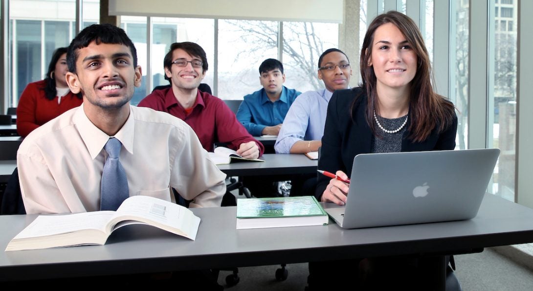 Students in a classroom at desks smiling