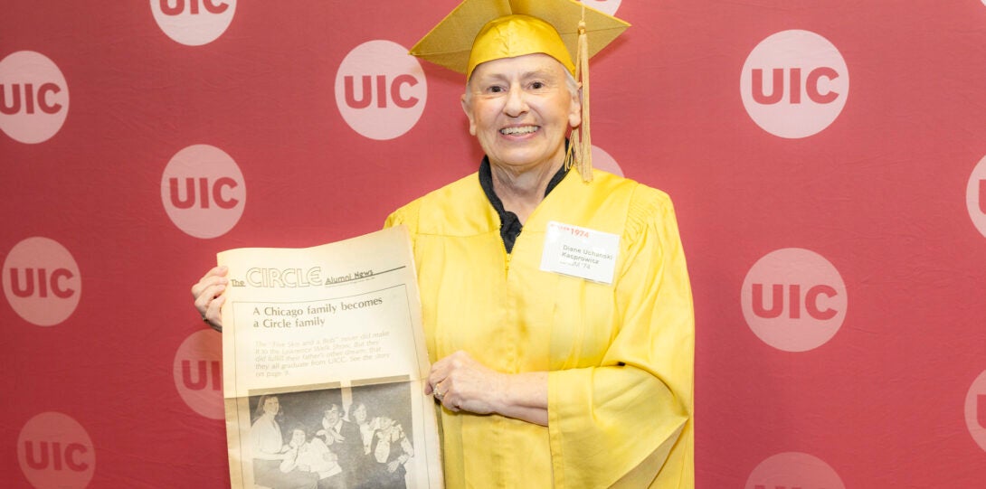 UIC Golden Grad holding a copy of the campus' alumni newspaper.